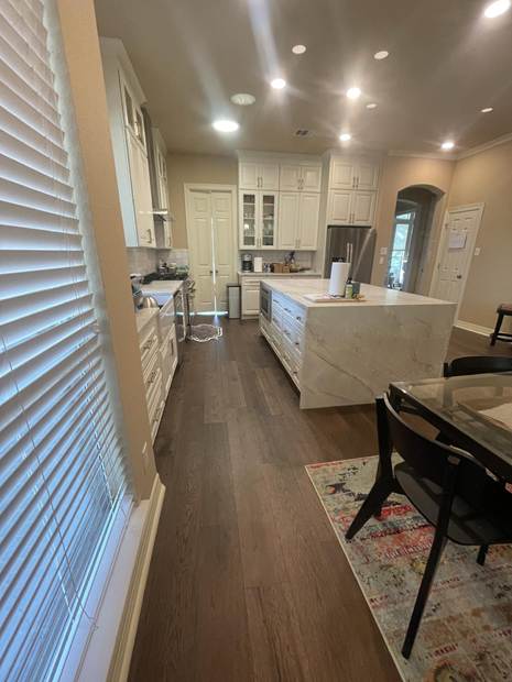 Second view of the completed white kitchen, showing the island and surrounding floor space.