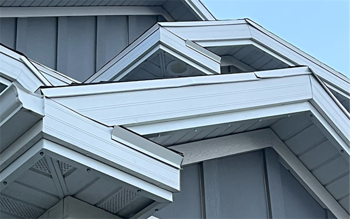 Title: Trimlight residential system - Description: Daytime close-up of white Trimlight channel following several roof peaks on a gray-sided house, with small light points beneath the trim.