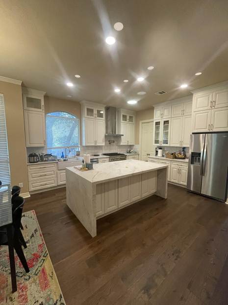 Completed House Doctors of Austin kitchen with white cabinetry, a central island and recessed lighting.