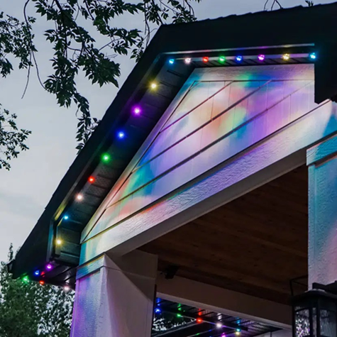 Title: Gemstone Lights residential track system - Description: Multicolored Gemstone Lights following the underside of a porch gable and casting colored light onto the siding.